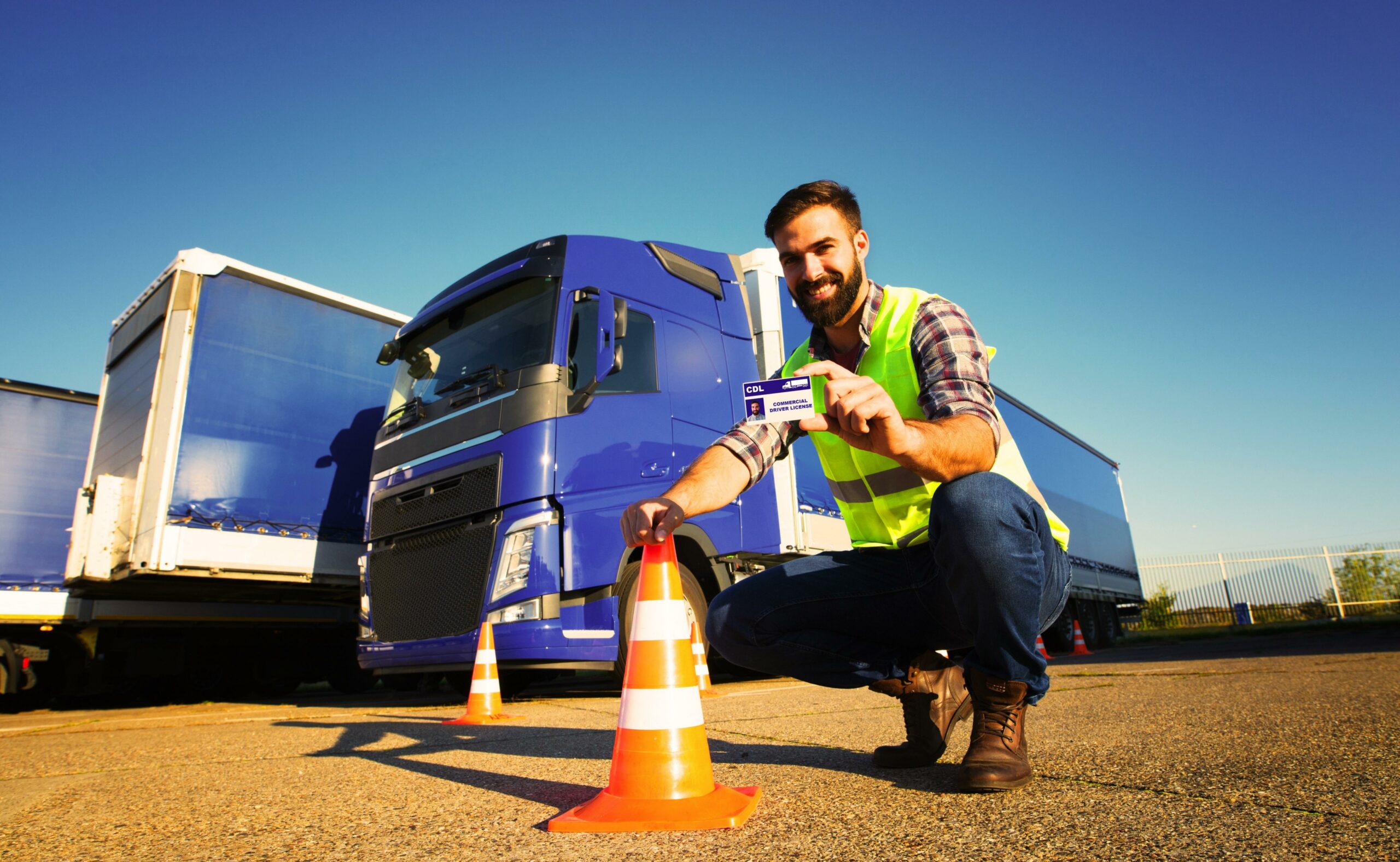 New truck driver showing his license with trucks behind him