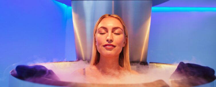 Happy young woman in a whole body cryotherapy cabin with her eyes closed