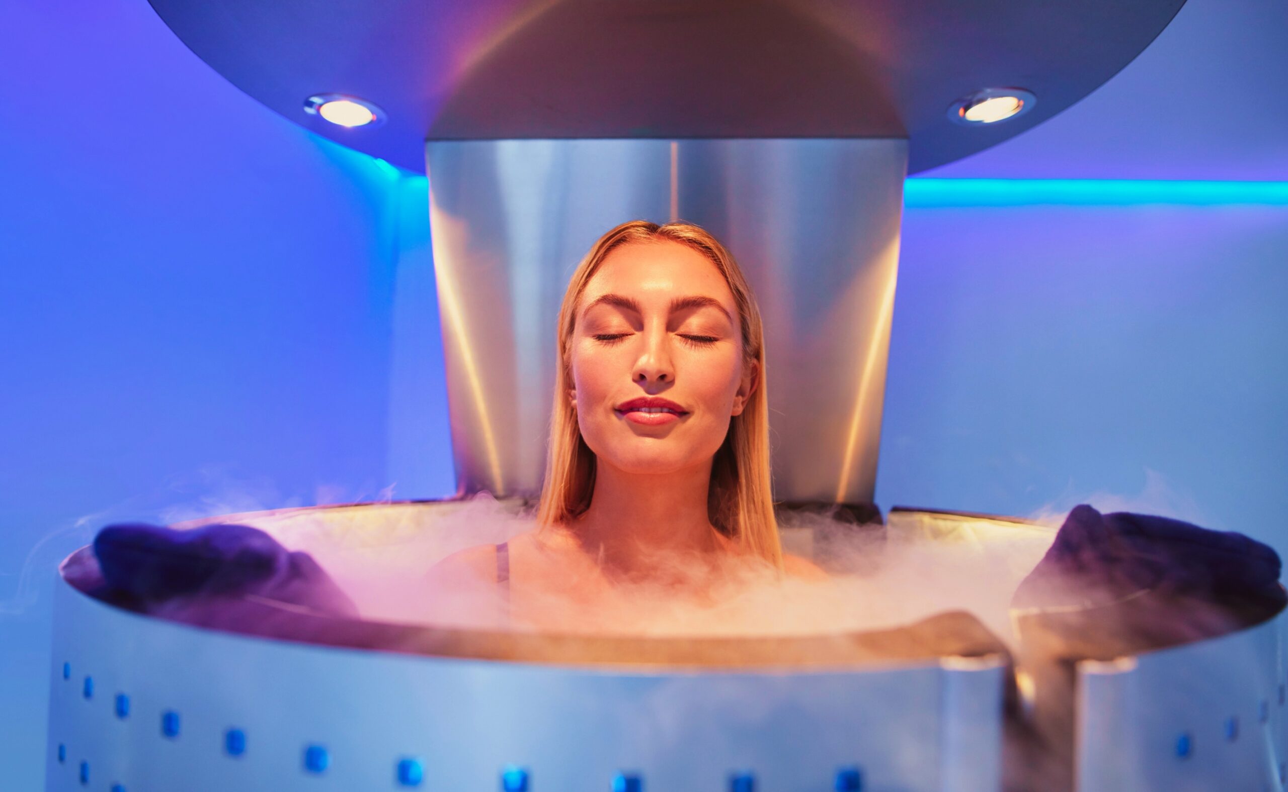 Happy young woman in a whole body cryotherapy cabin with her eyes closed