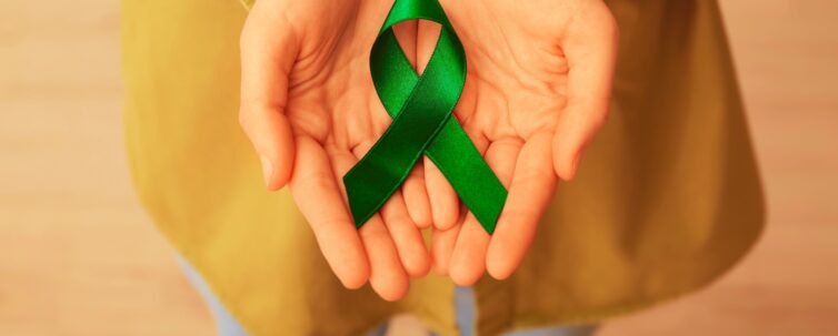 woman holding green ribbon close up. liver cancer