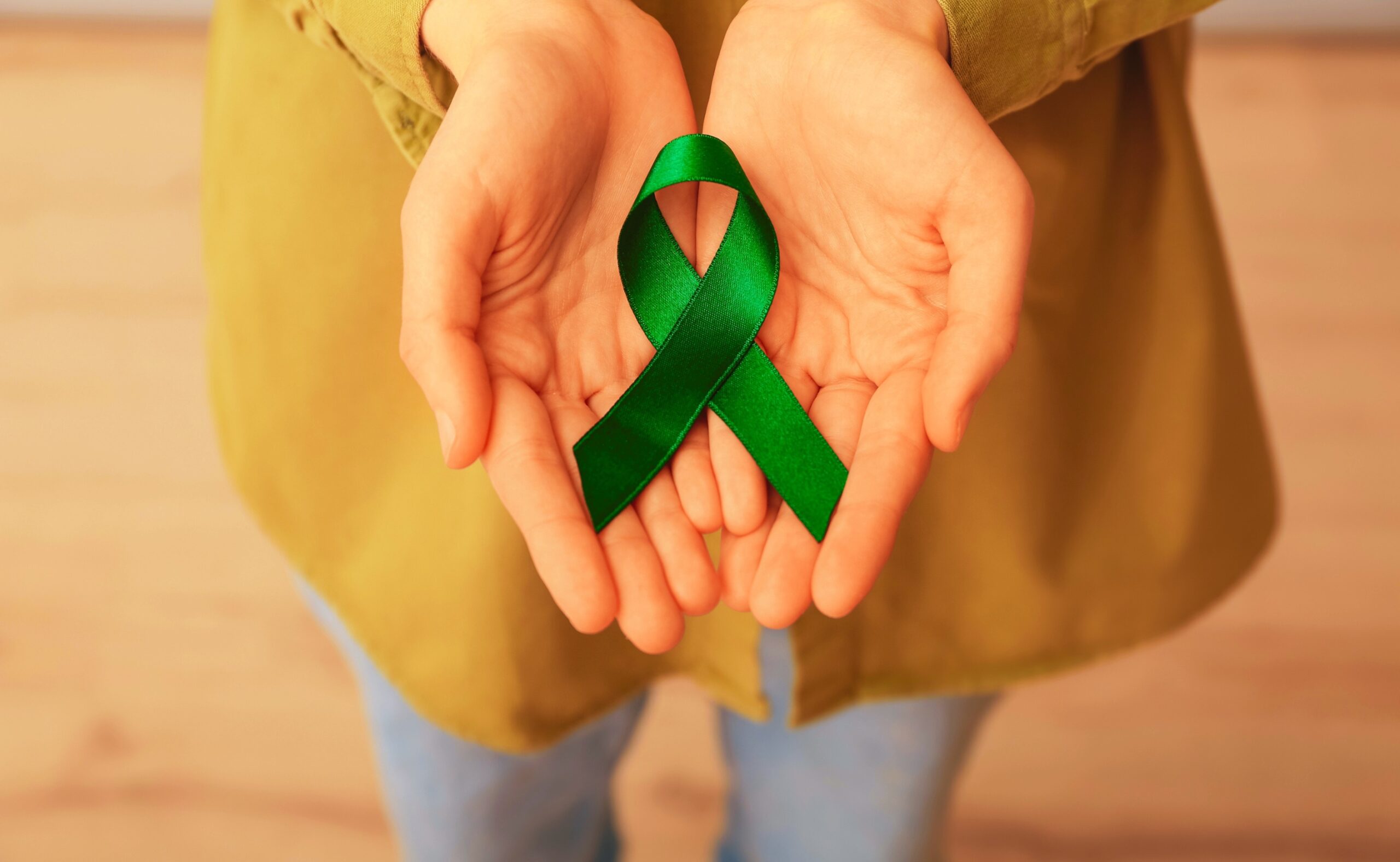 woman holding green ribbon close up. liver cancer