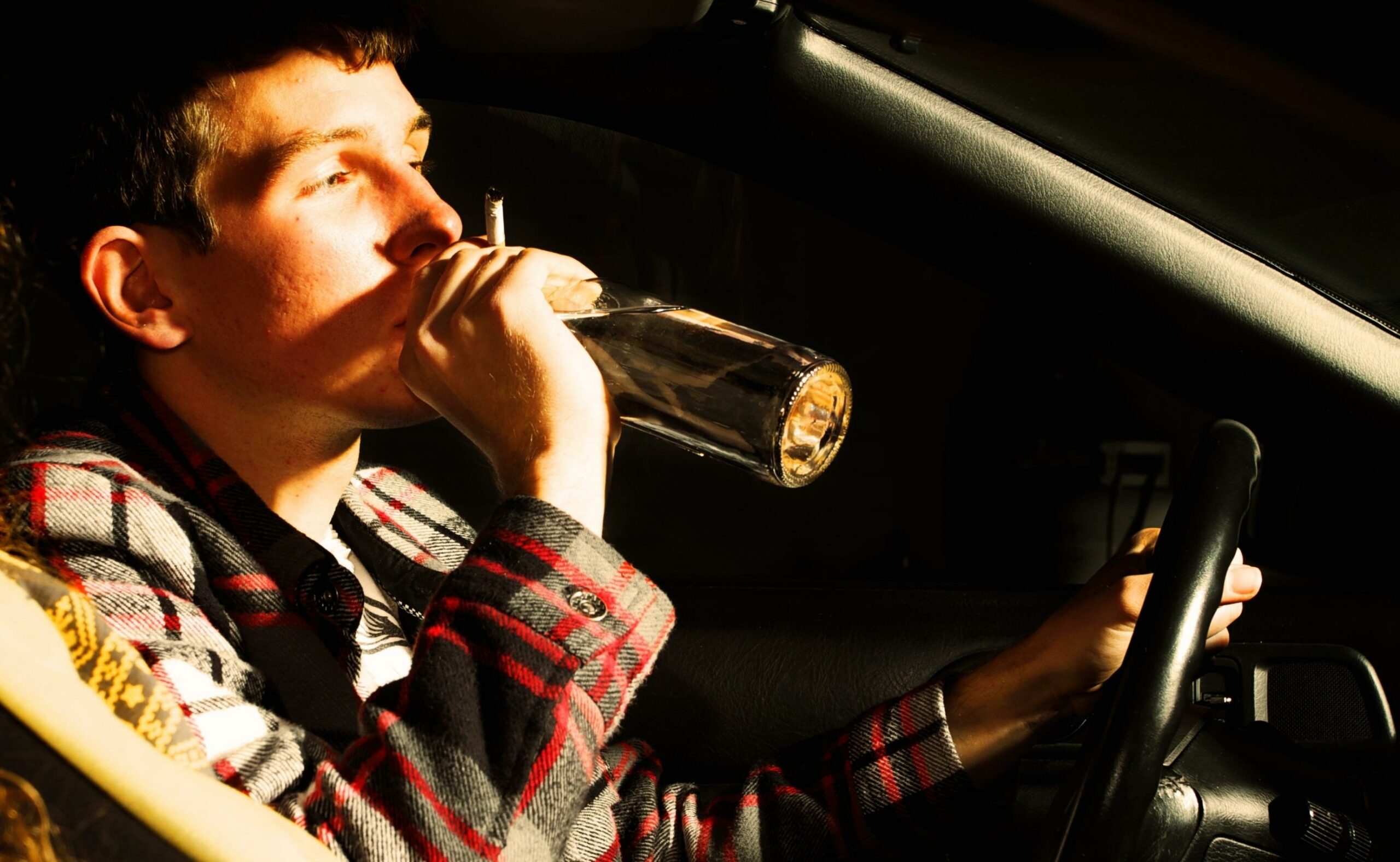 teenager drinking alcohol inside a car