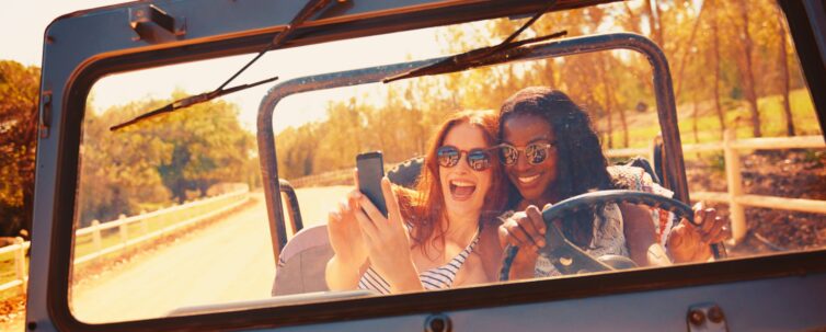 two attractive young women snapping a selfie in the car