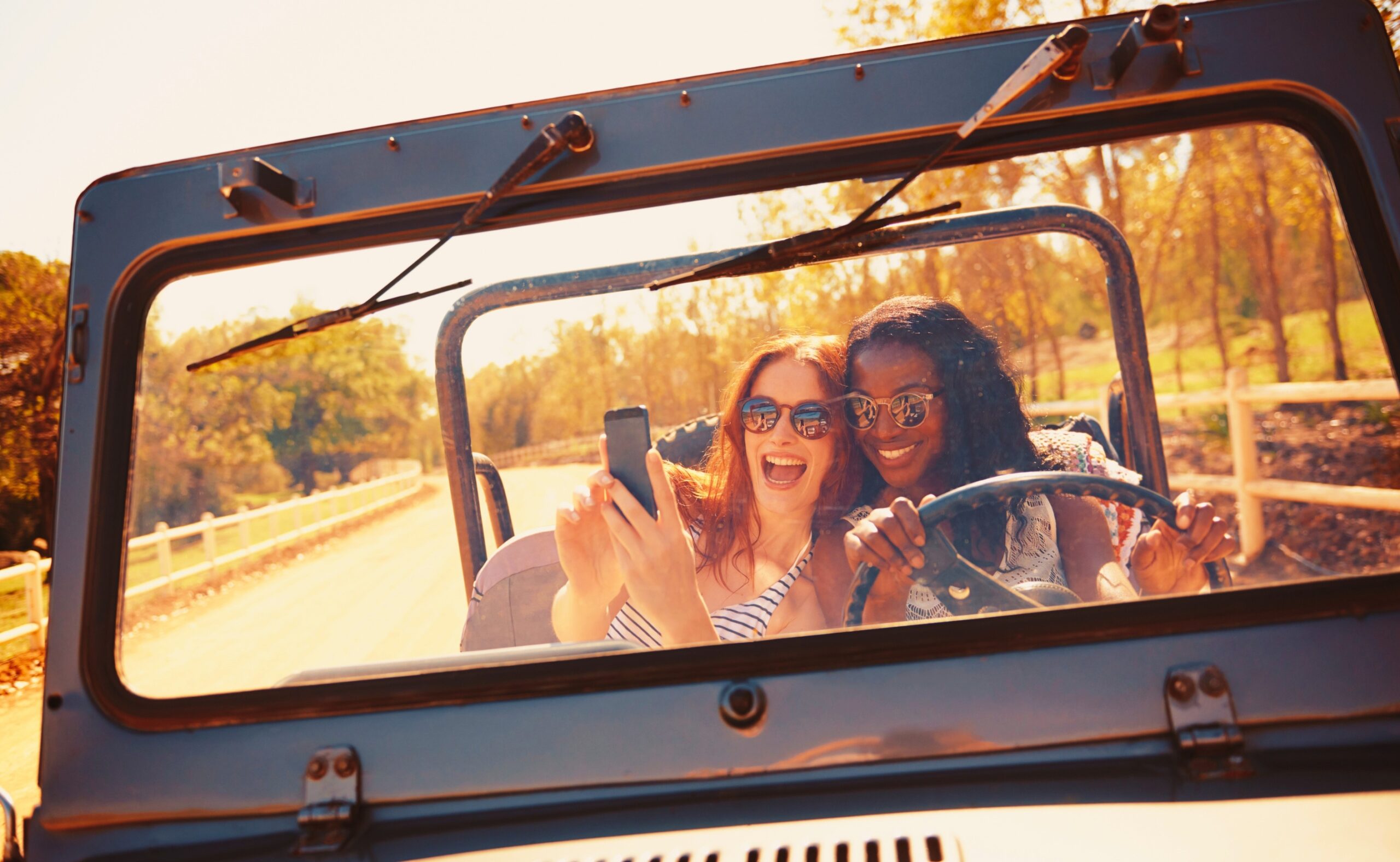 two attractive young women snapping a selfie in the car