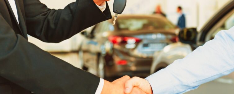 two men shaking hands while the other man on suit was handing a car keys