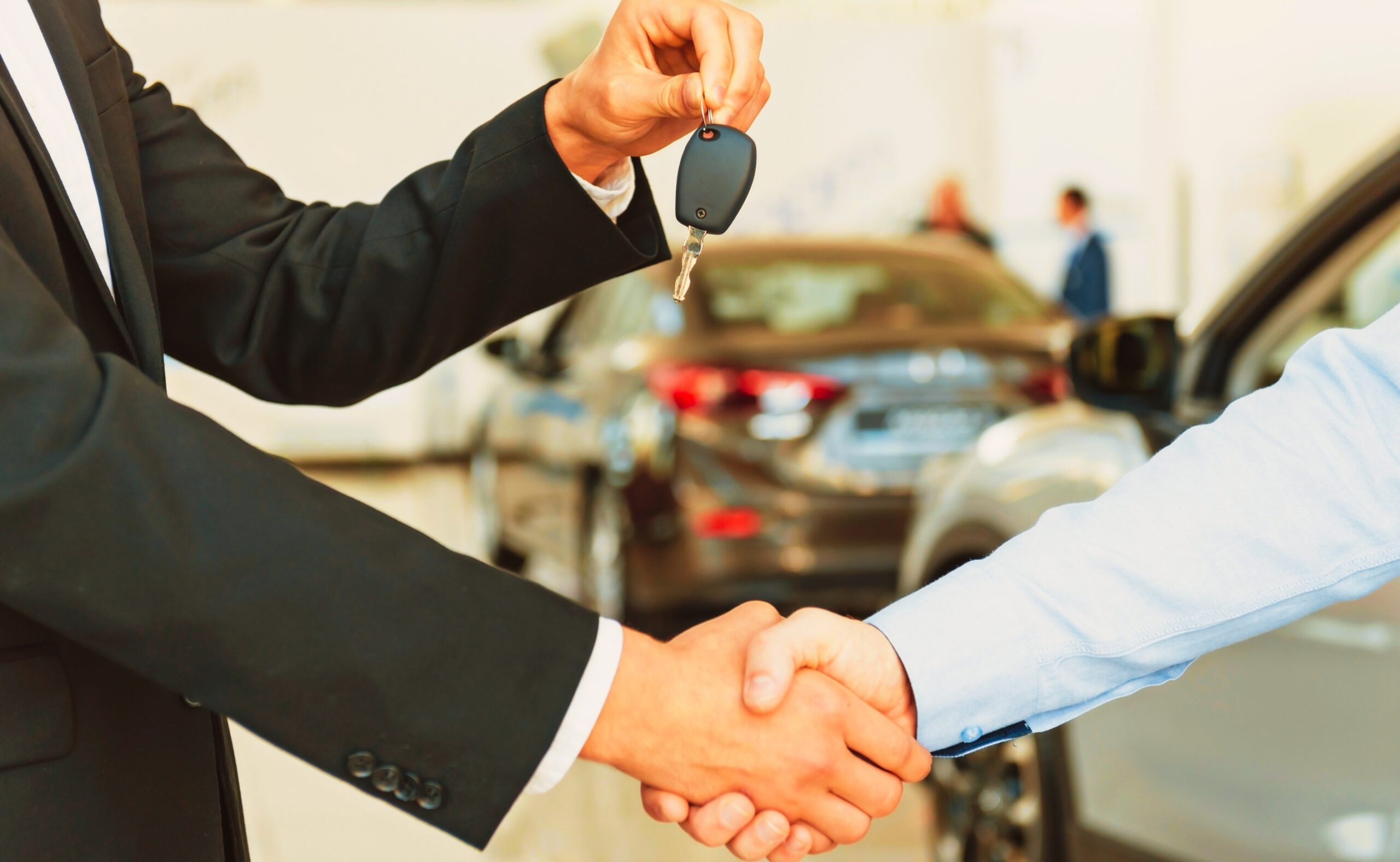 two men shaking hands while the other man on suit was handing a car keys