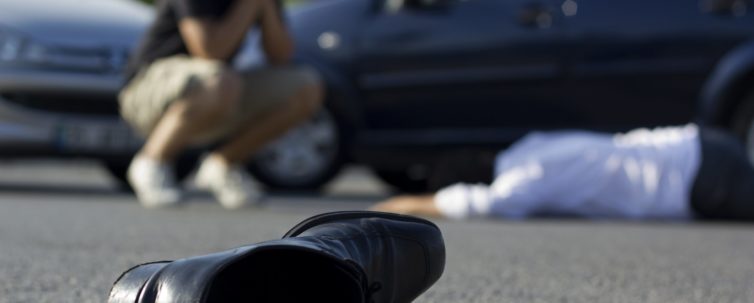 shocked and worried driver looking over a car accident victim on the pavement