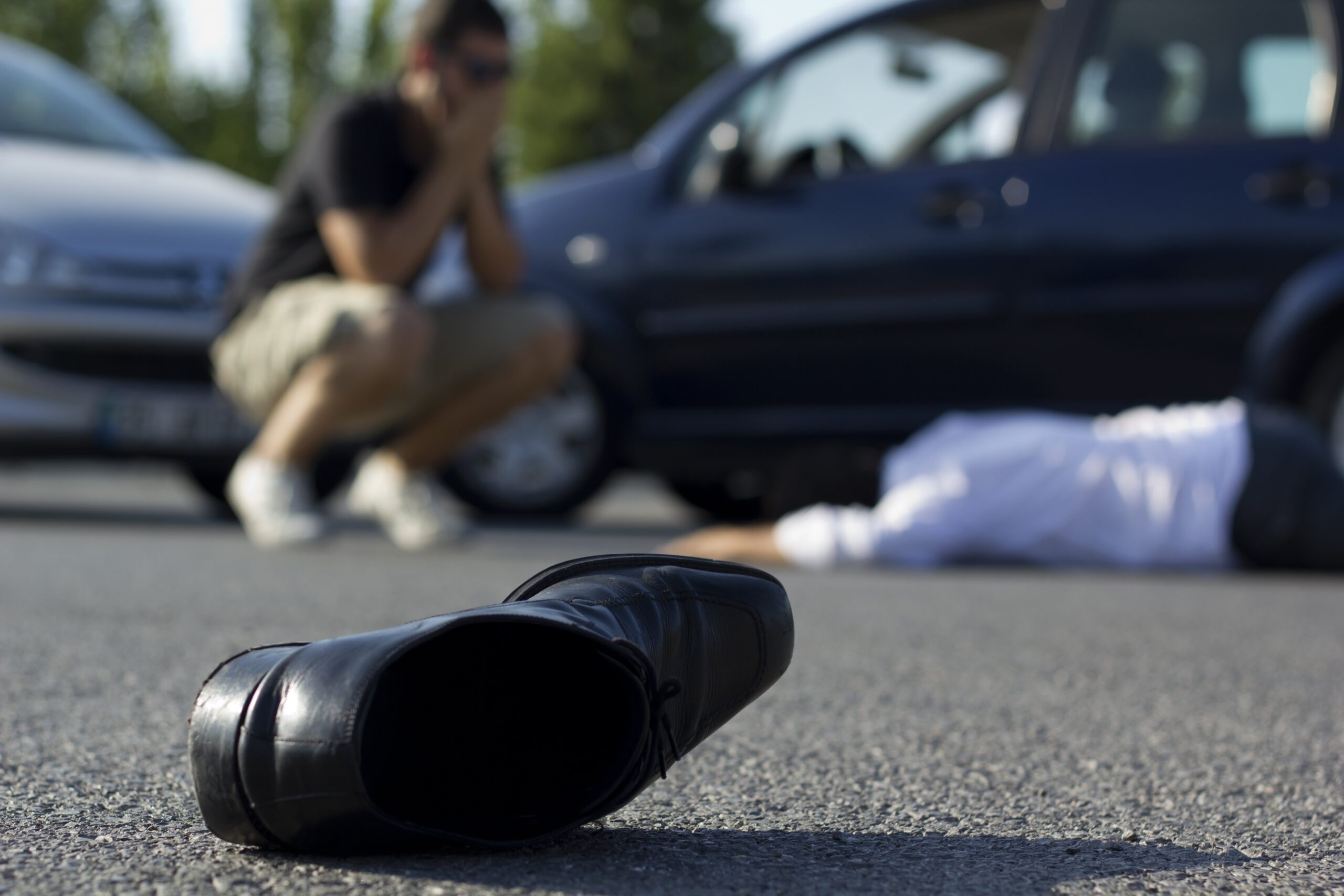 shocked and worried driver looking over a car accident victim on the pavement