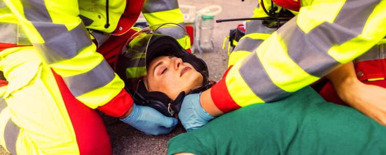 Paramedics removing helmet of injured motorcyclist woman after an accident