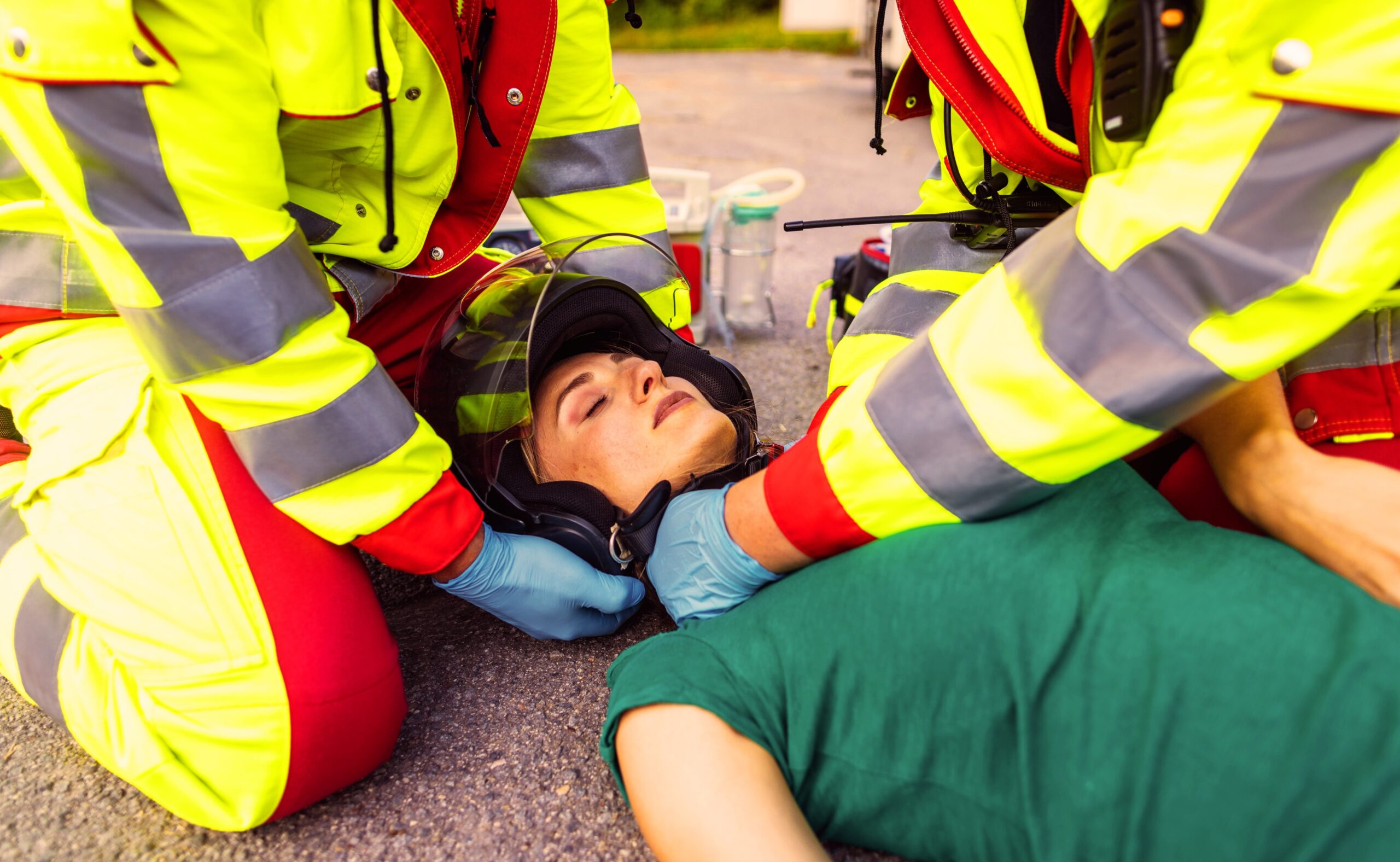 Paramedics removing helmet of injured motorcyclist woman after an accident