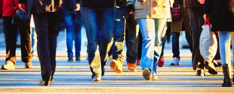 Zebra crossing with motion blurred crowd brightly lit by low sun