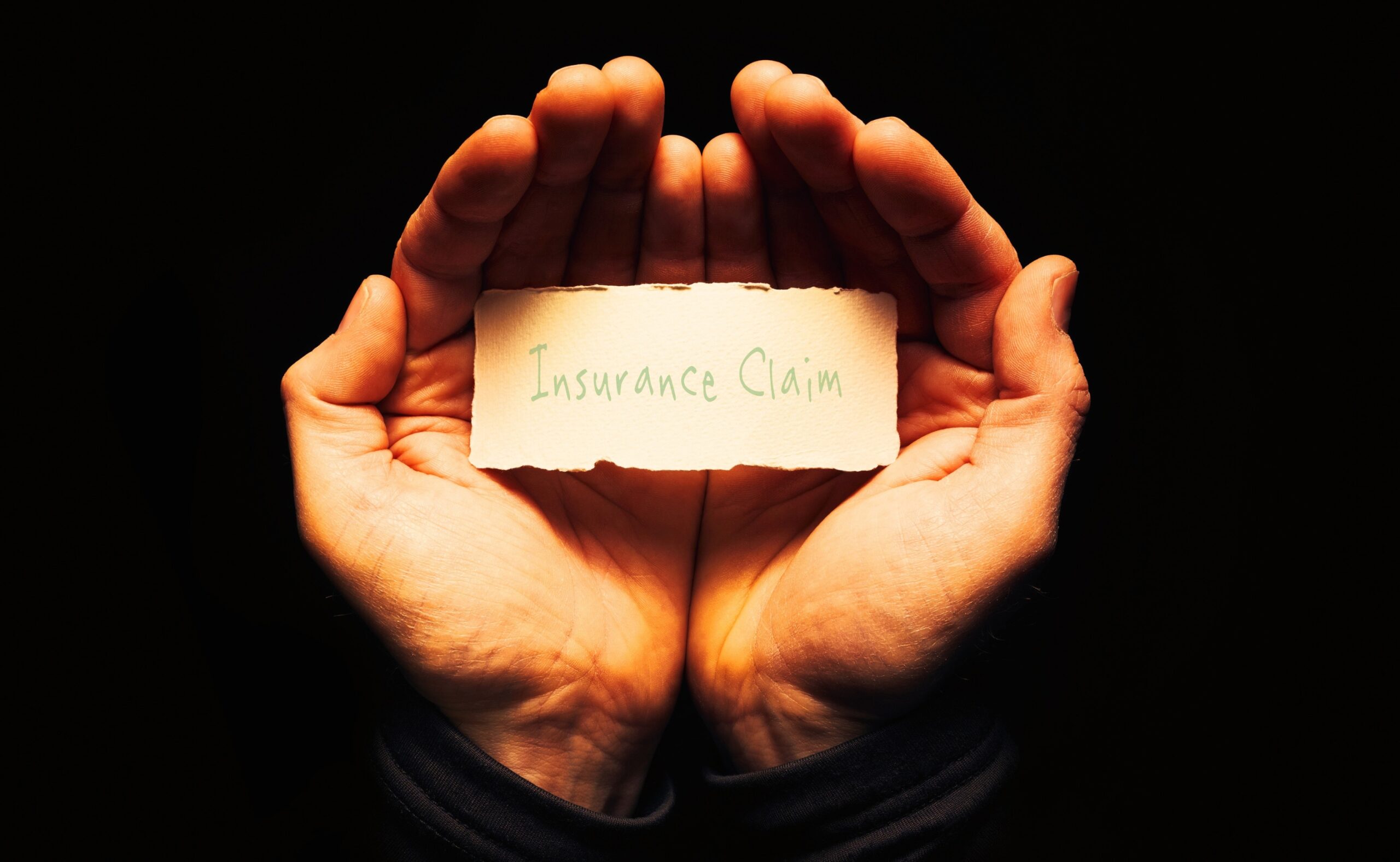 Insurance Claim written on a paper and held by two hands