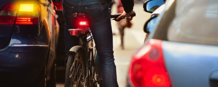 A man riding a bike in the middle of cars on the road