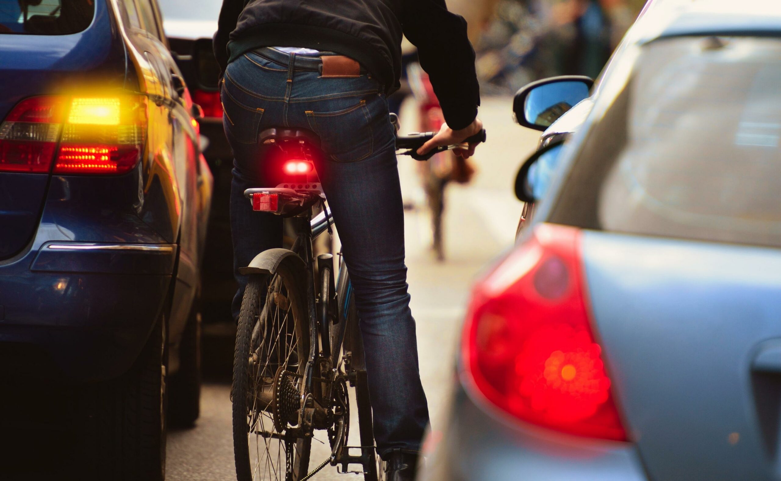 A man riding a bike in the middle of cars on the road