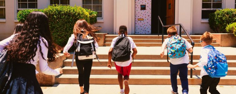 Children with their backpacks running to get inside school