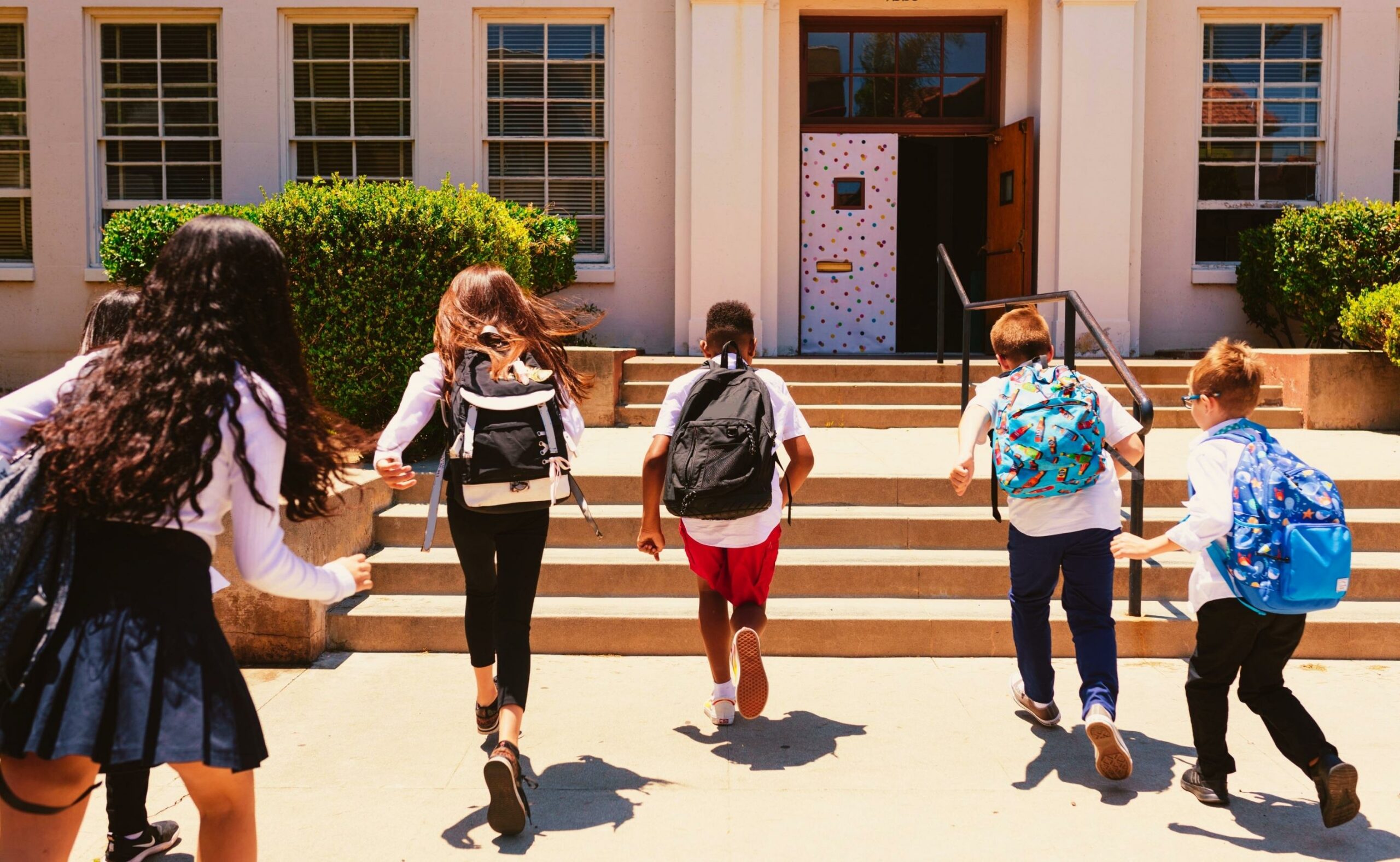 Children with their backpacks running to get inside school