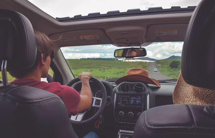 a man driving with the sunroof open