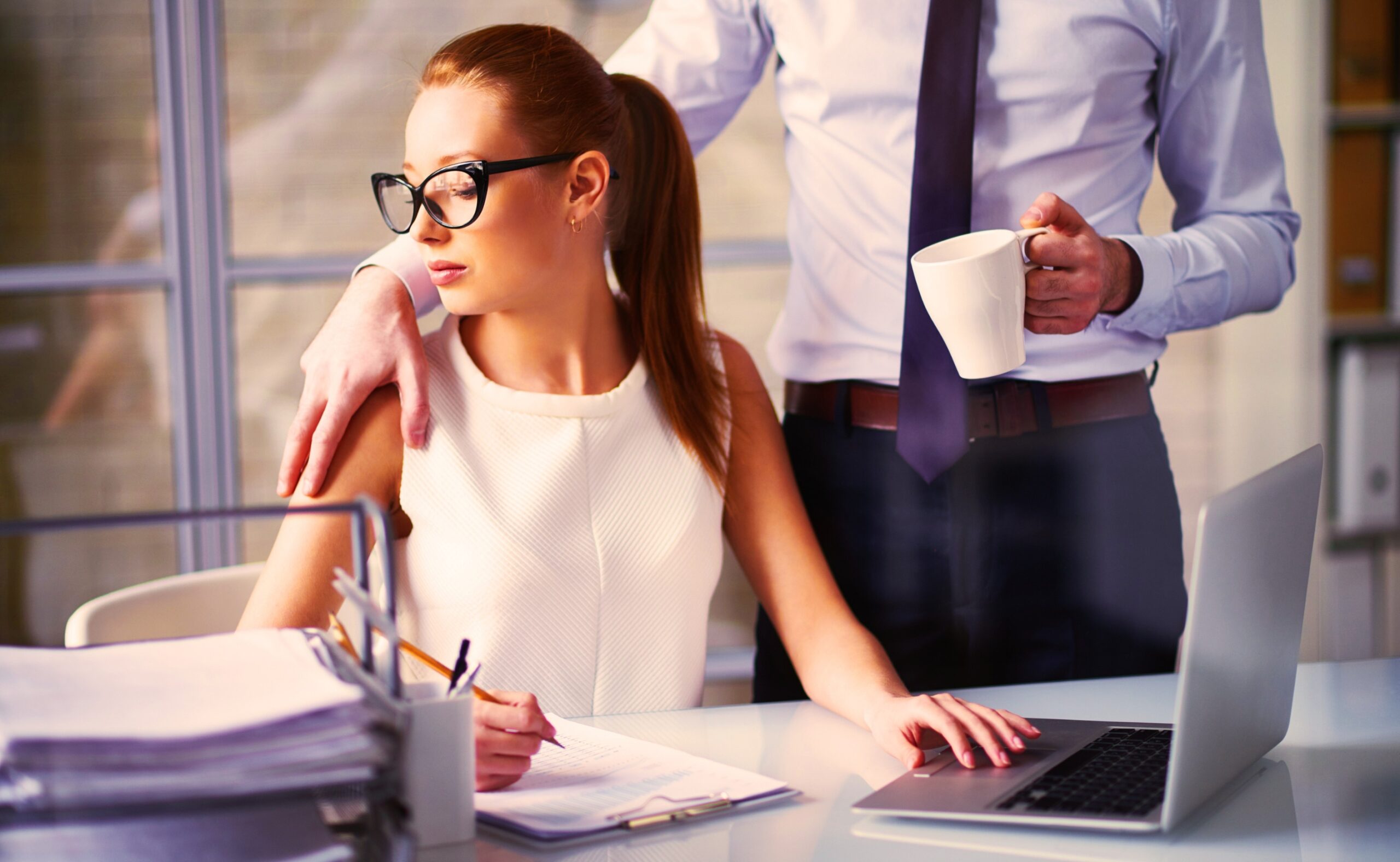 a man touching a woman's shoulder while working in the office