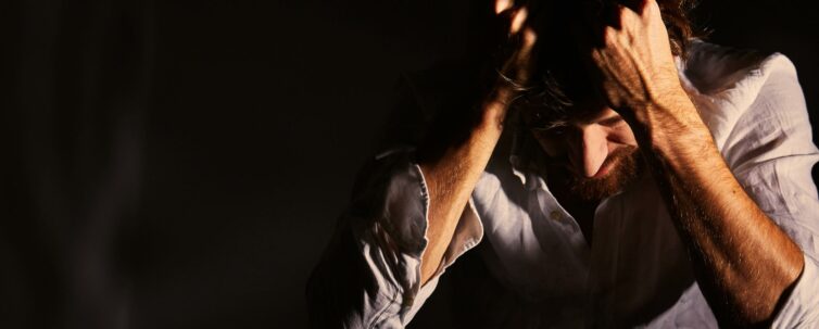 Man suffering emotional pain holding head in his hands