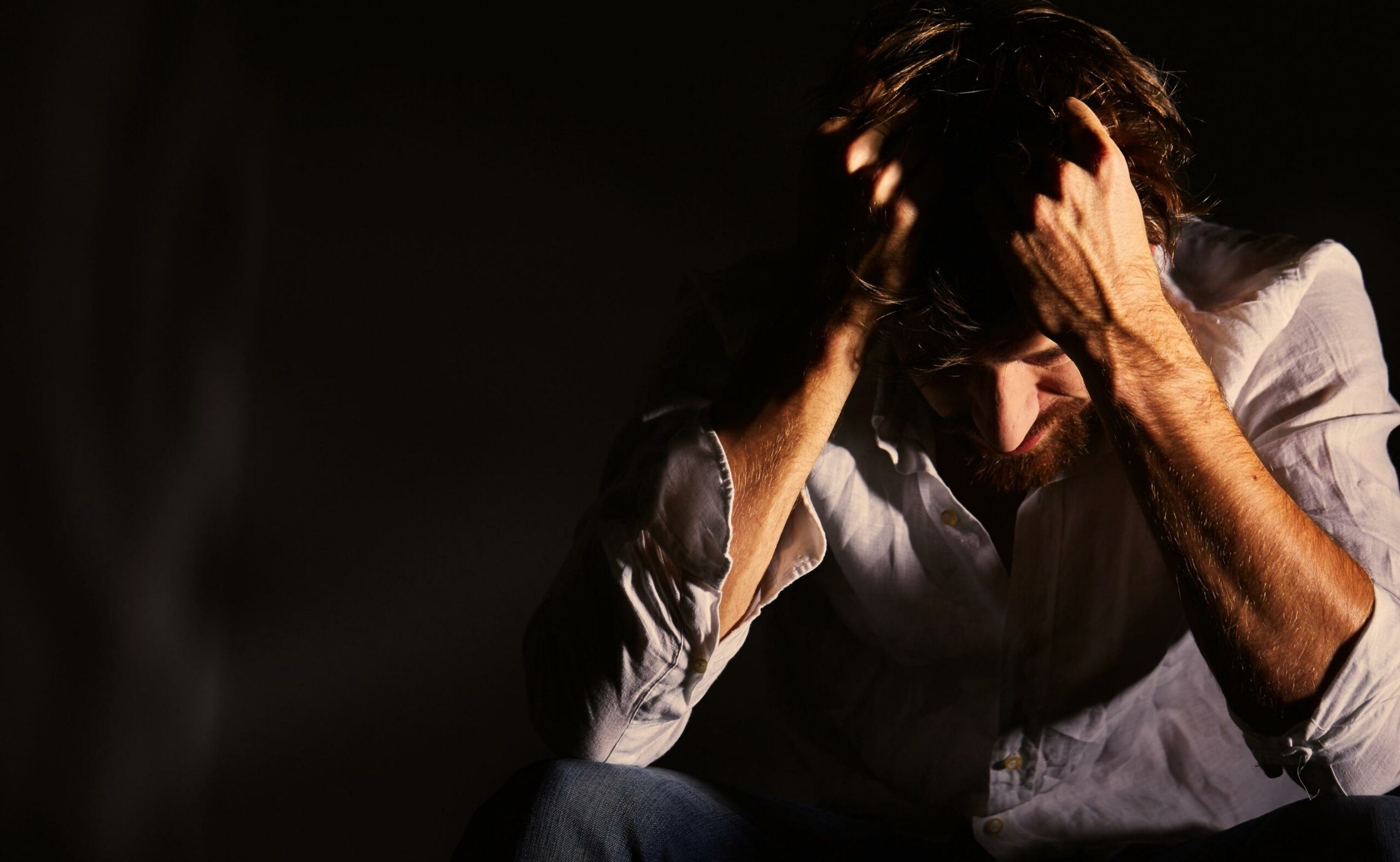 Man suffering emotional pain holding head in his hands