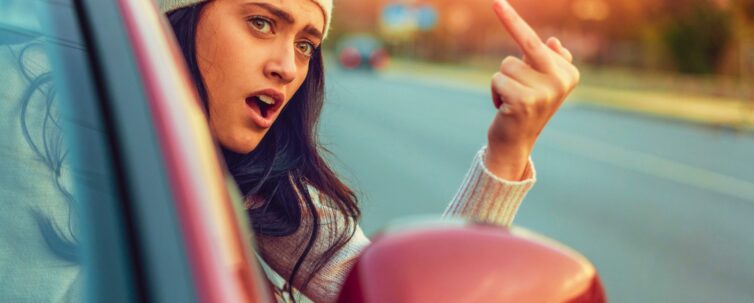 Young female using obscene gesture while driving