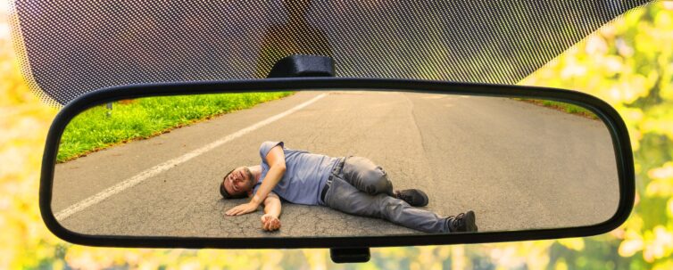 Hit and run concept. View on injured man on road in rear mirror of a car.