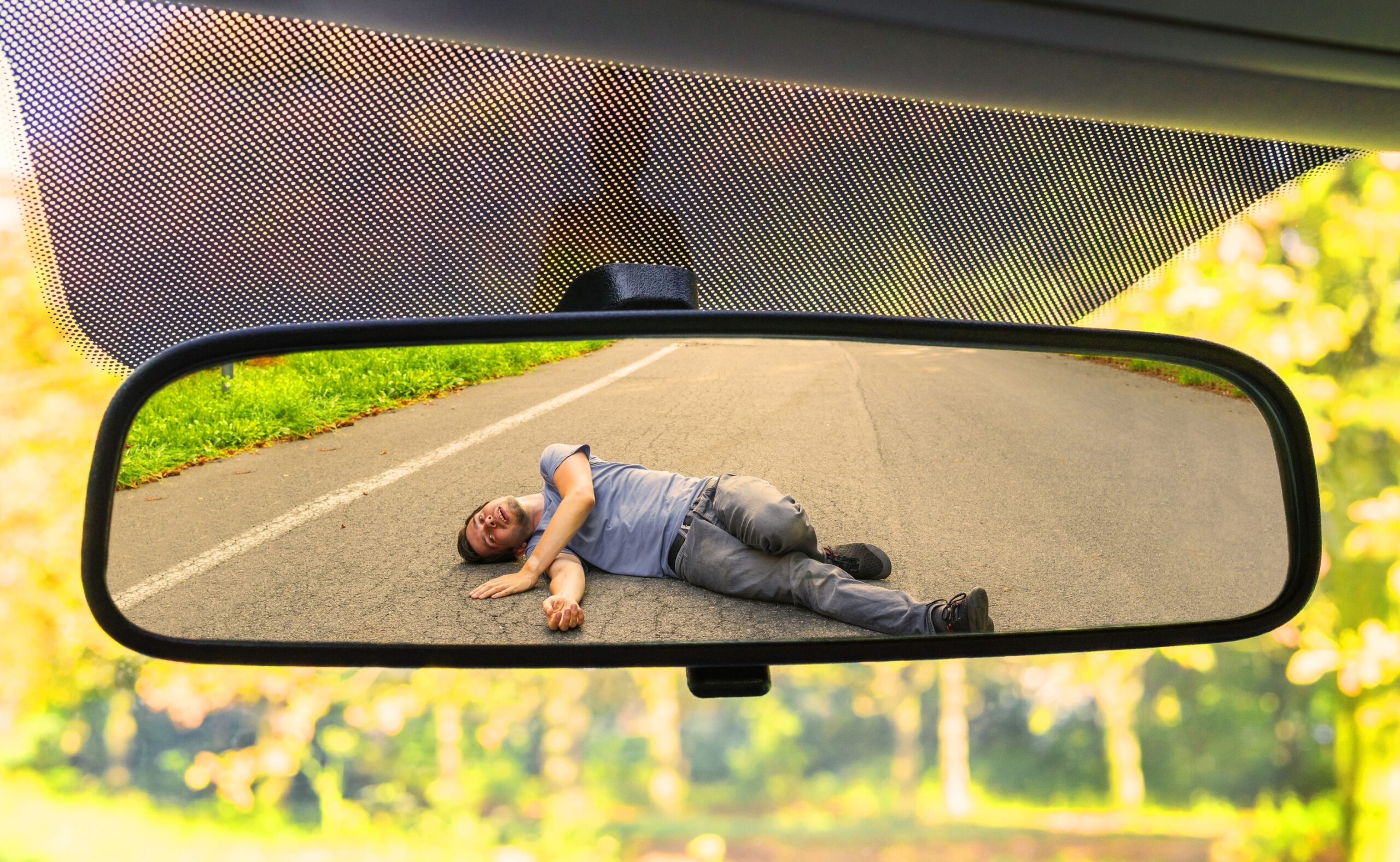 Hit and run concept. View on injured man on road in rear mirror of a car.