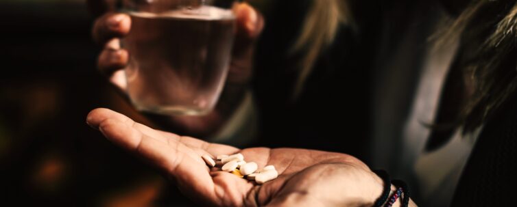 gloomy image of a woman taking several pills to treat depression