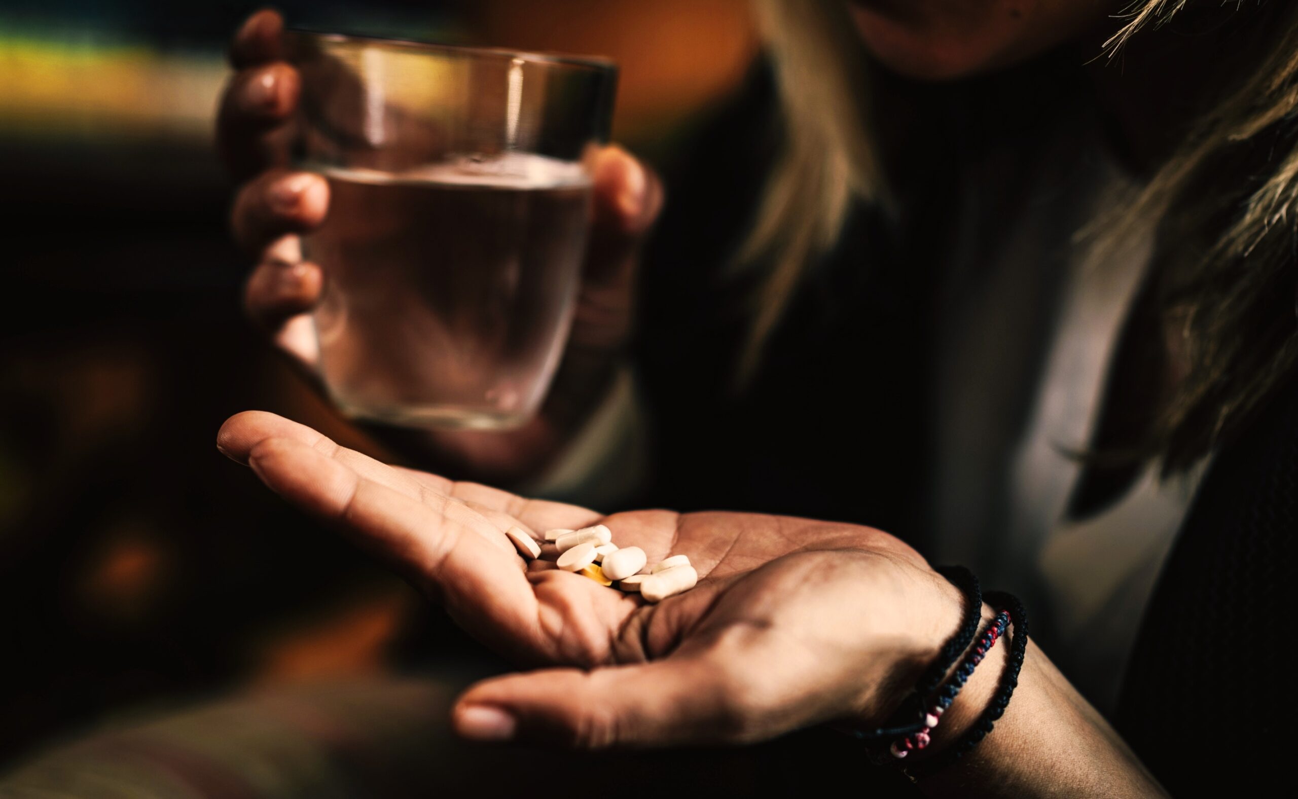 gloomy image of a woman taking several pills to treat depression