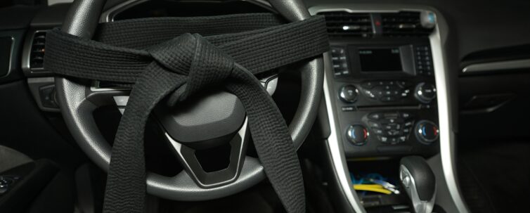 Black belt tied around a car's steering wheel. defensive driving concept