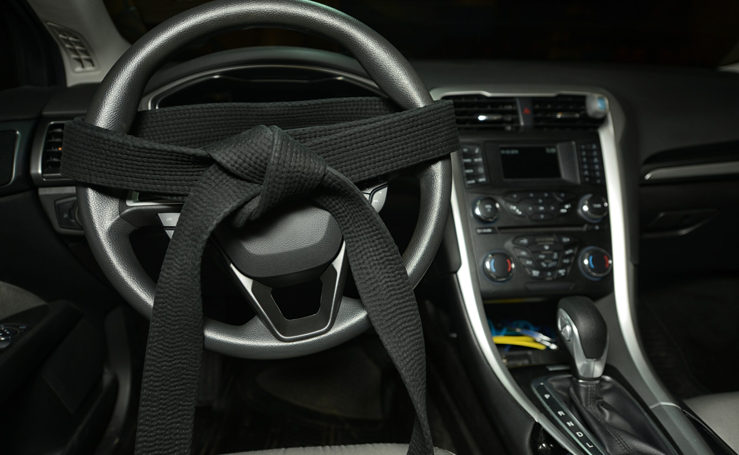 Black belt tied around a car's steering wheel. defensive driving concept
