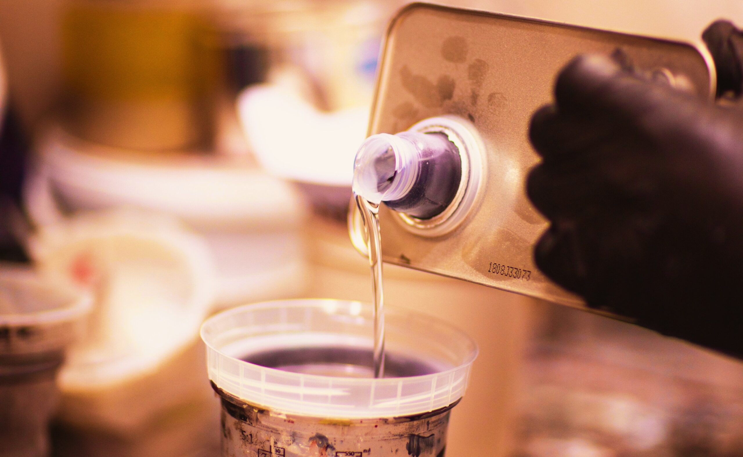 Pouring a paint thinner in a mixing container in a workshop