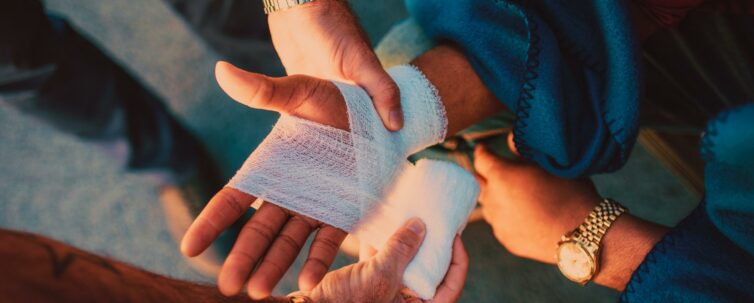 Medic applying bandage on worker's hand after injury