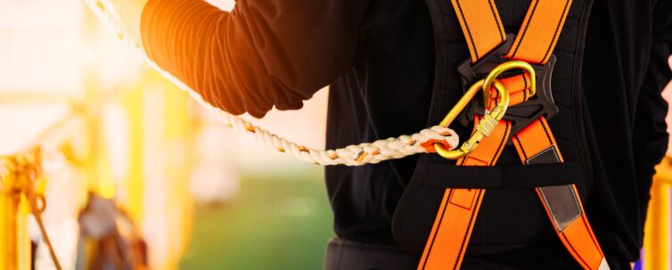 Construction worker wearing safety harness and safety line and working high place at industrial site