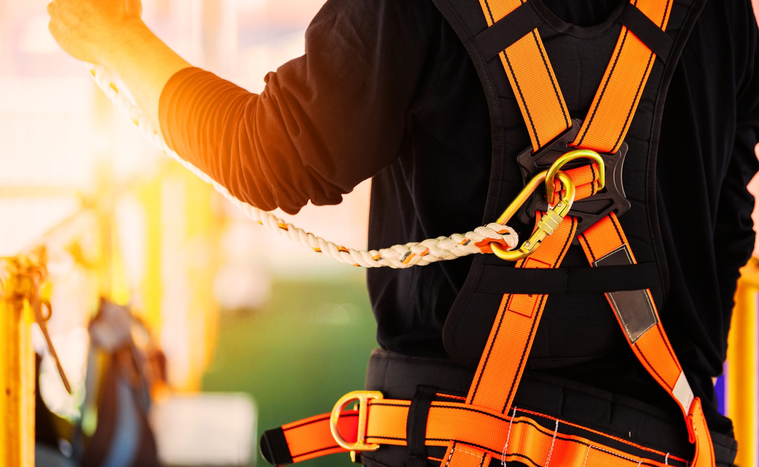 Construction worker wearing safety harness and safety line and working high place at industrial site