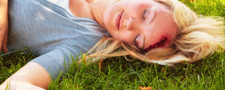 A woman lying on the group with a head injury