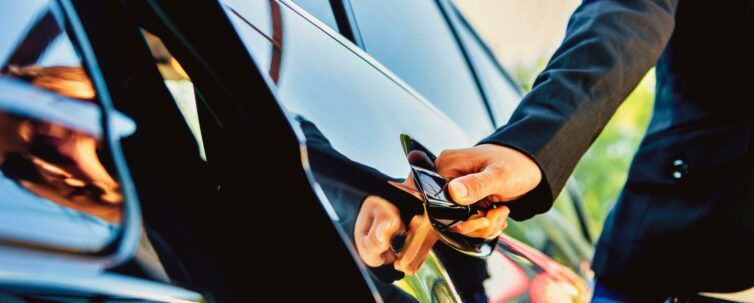 Female chauffer opening luxury car door