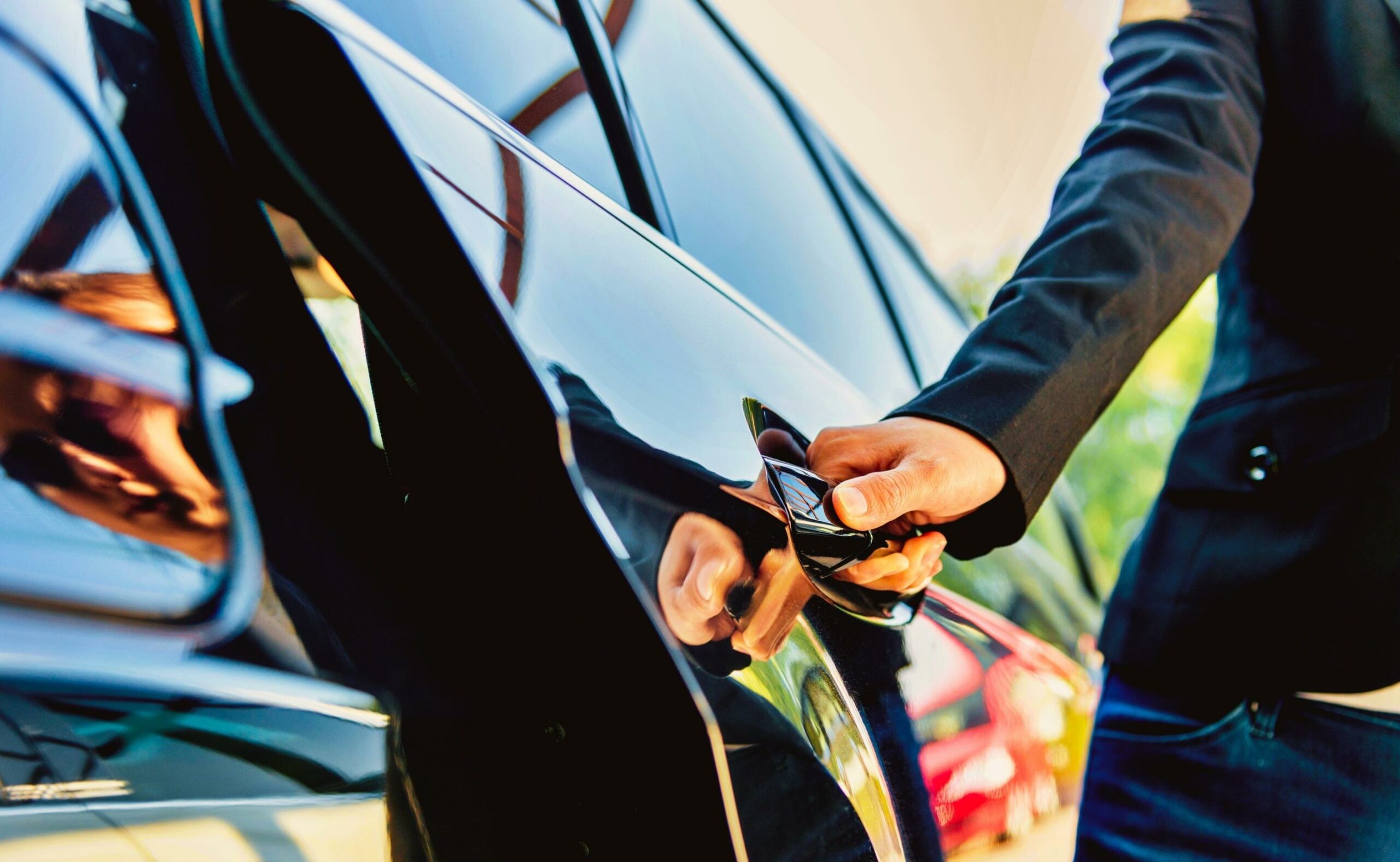 Female chauffer opening luxury car door