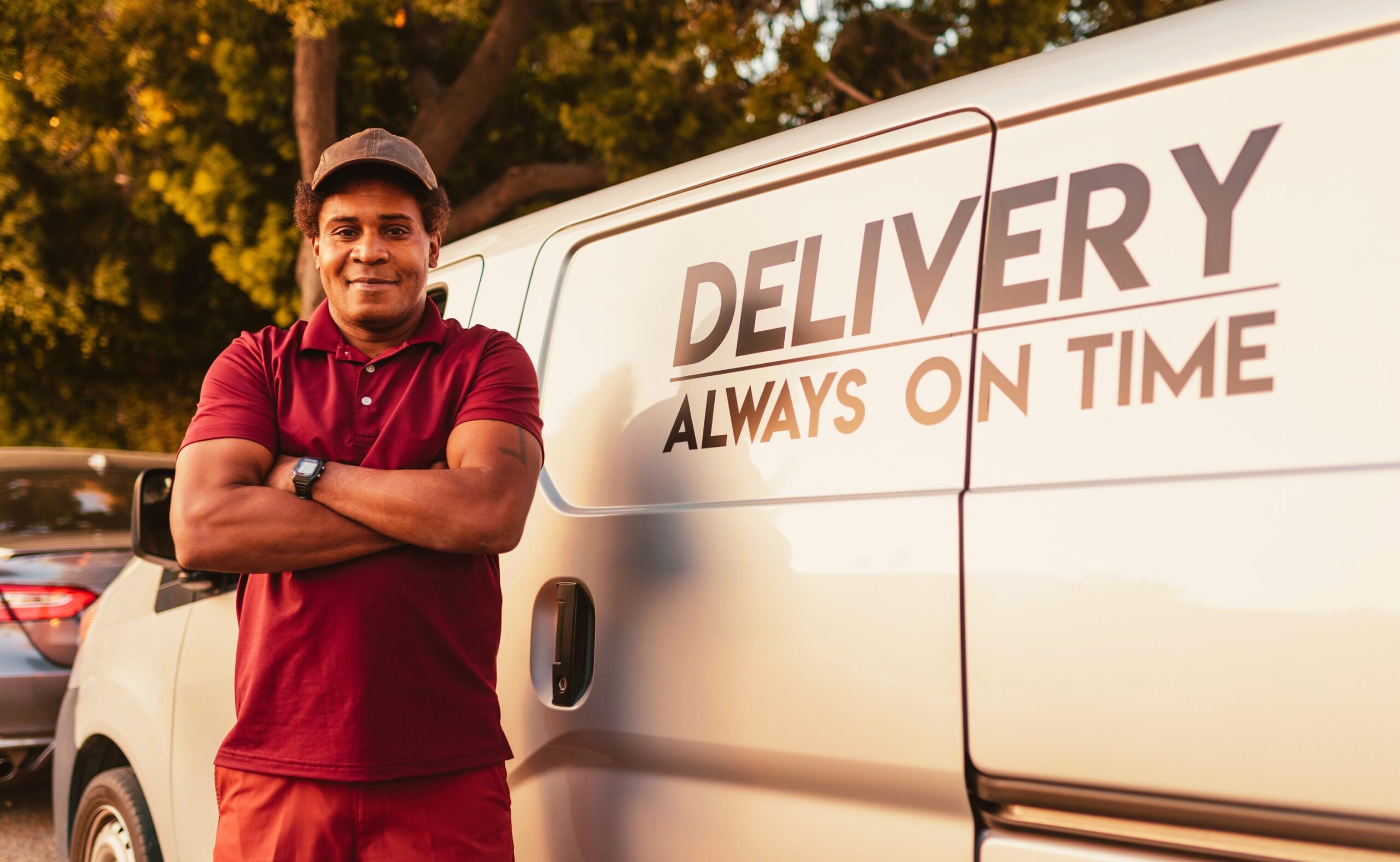 Man in Red and Black Polo Shirt Standing Beside White Van