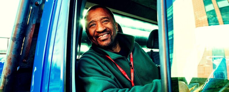 Matured truck driver smiling at the camera by his truck window