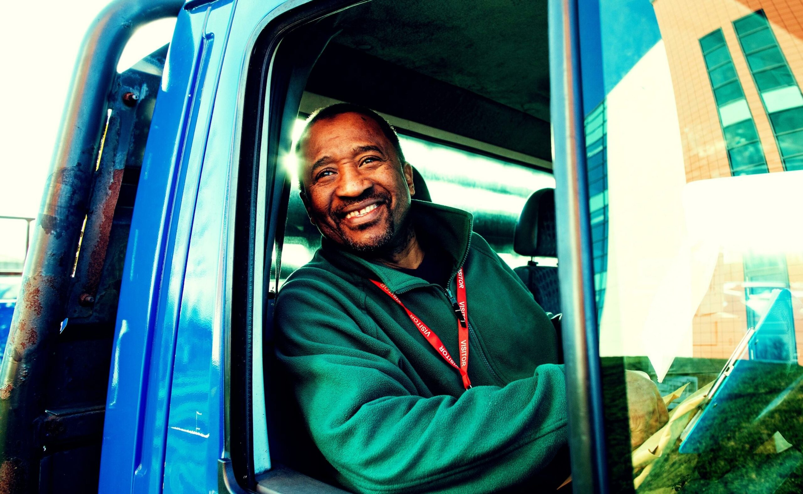 Matured truck driver smiling at the camera by his truck window