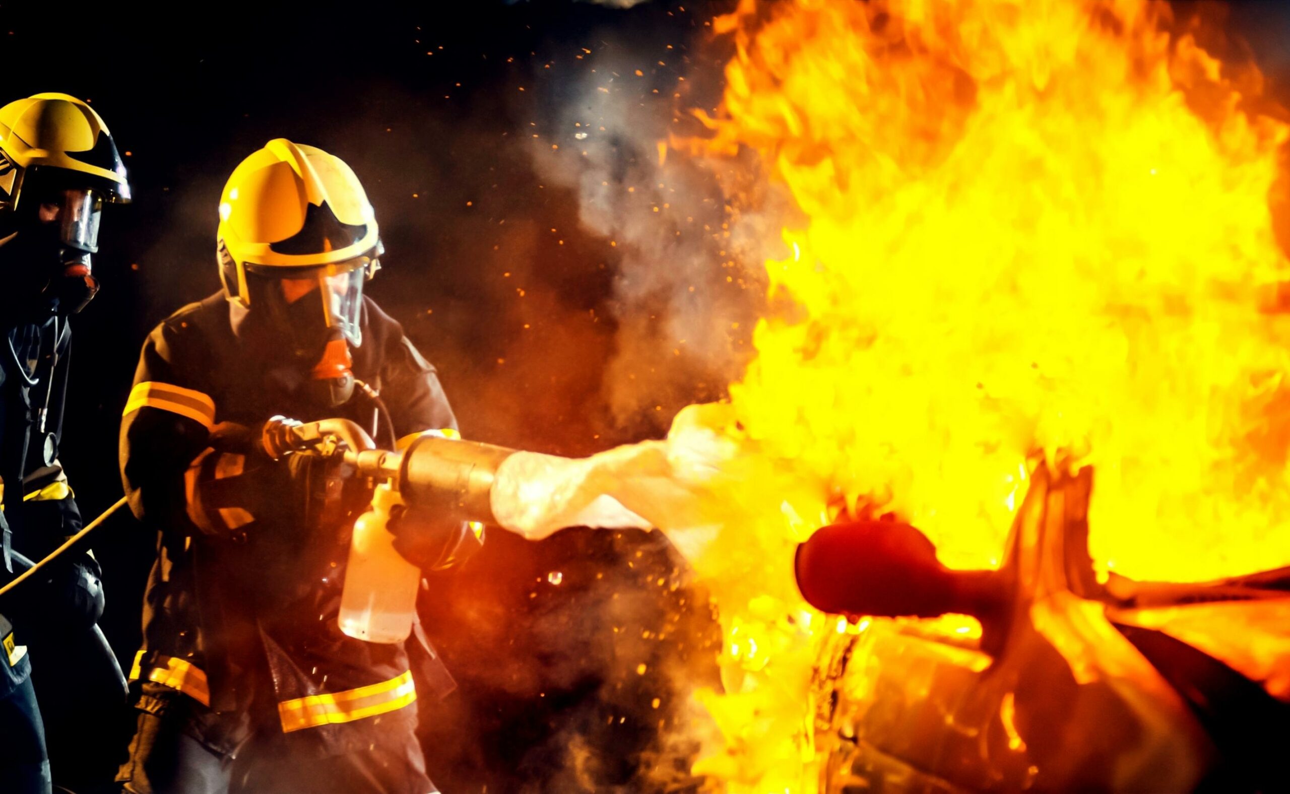 Firefighters extinguishing vehicle fire with foam after accident