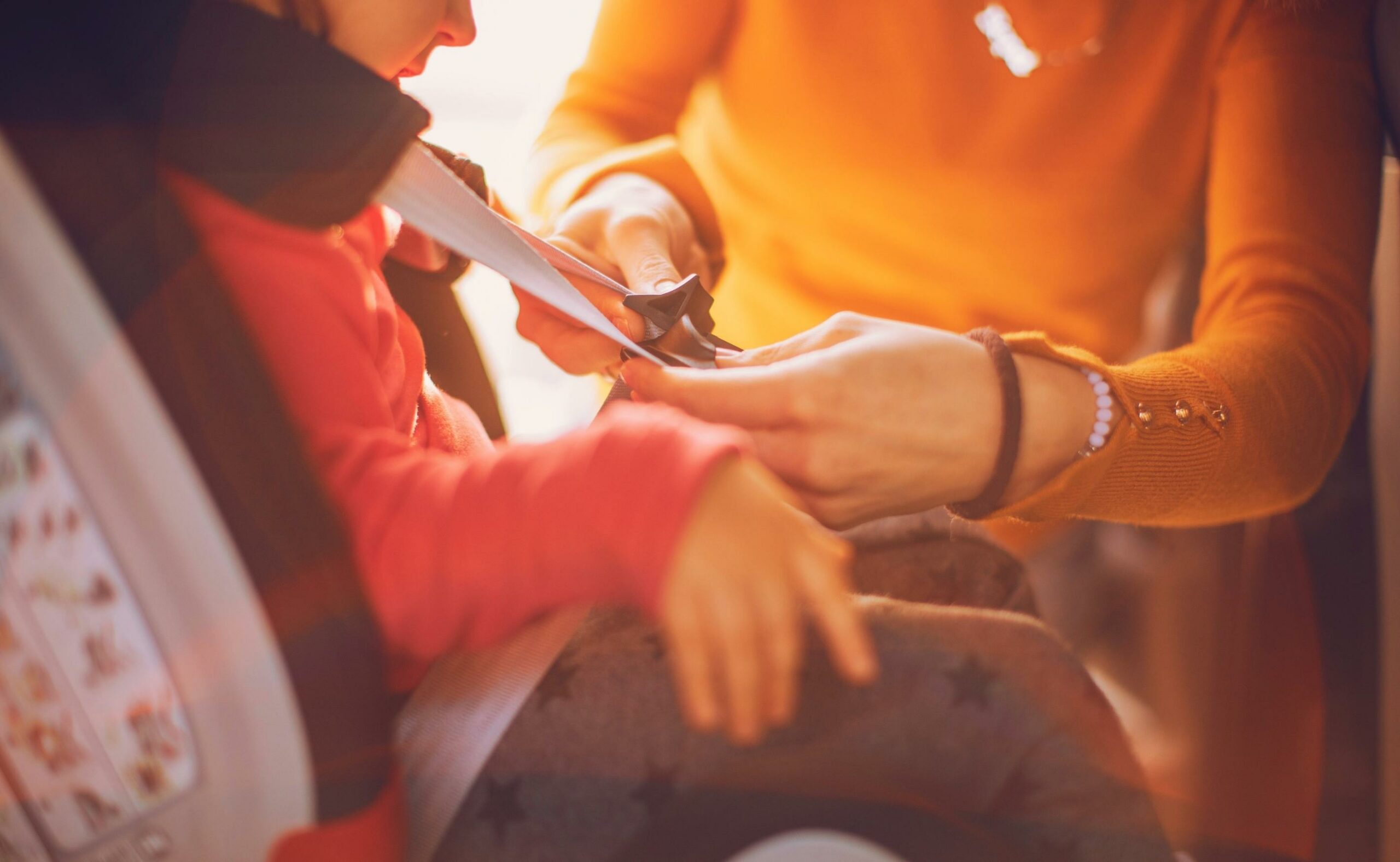 Mother strapping her child in the car seat