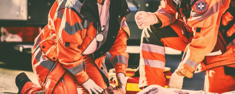 Female and male paramedic kneeling beside dead woman lying on a street, victim of car accident