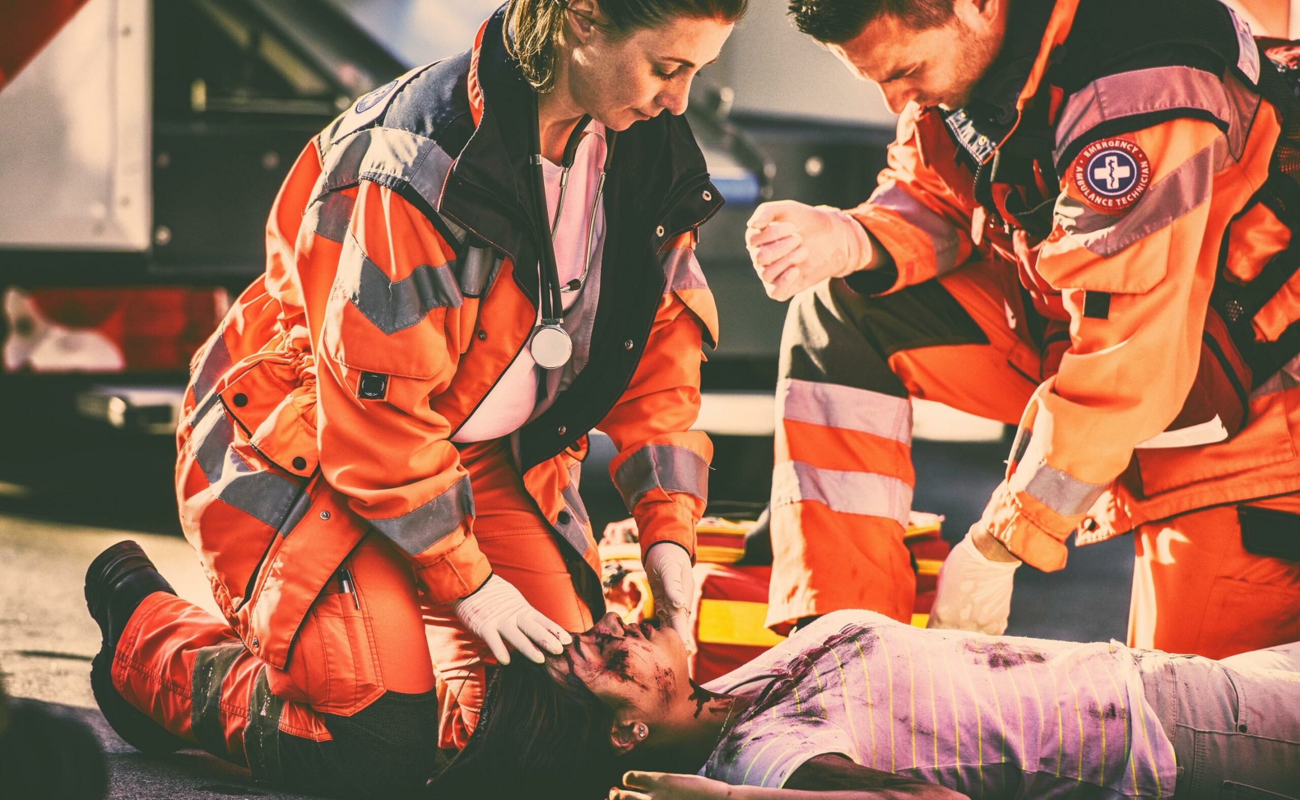 Female and male paramedic kneeling beside dead woman lying on a street, victim of car accident