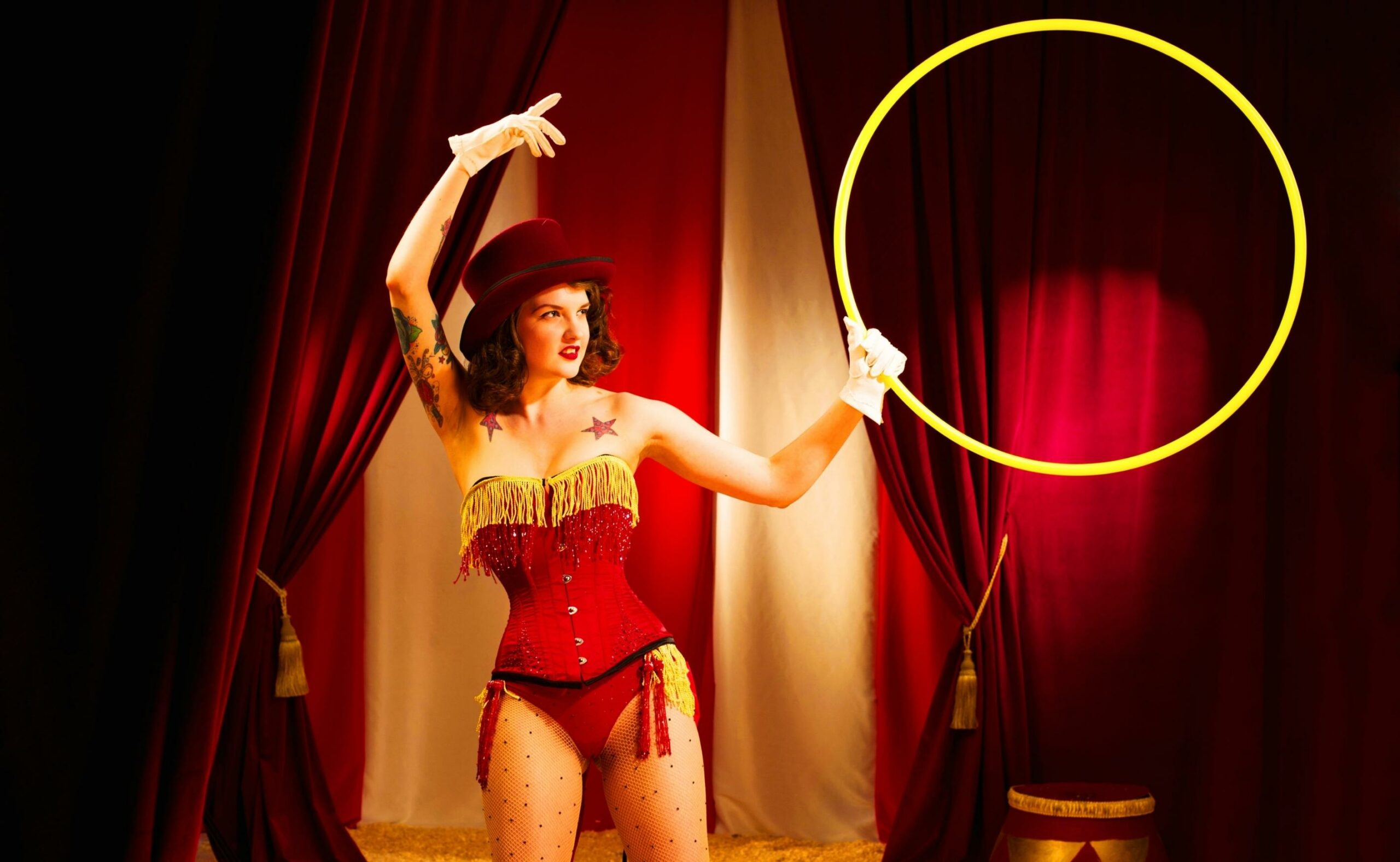 Burlesque ringmaster holds a hoop for you to jump through