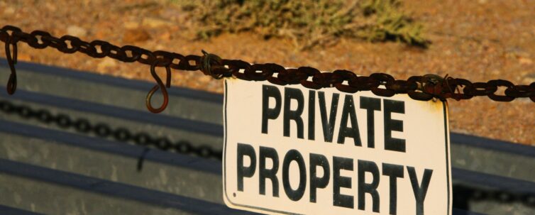 Private property sign hanging on a chain restricting access