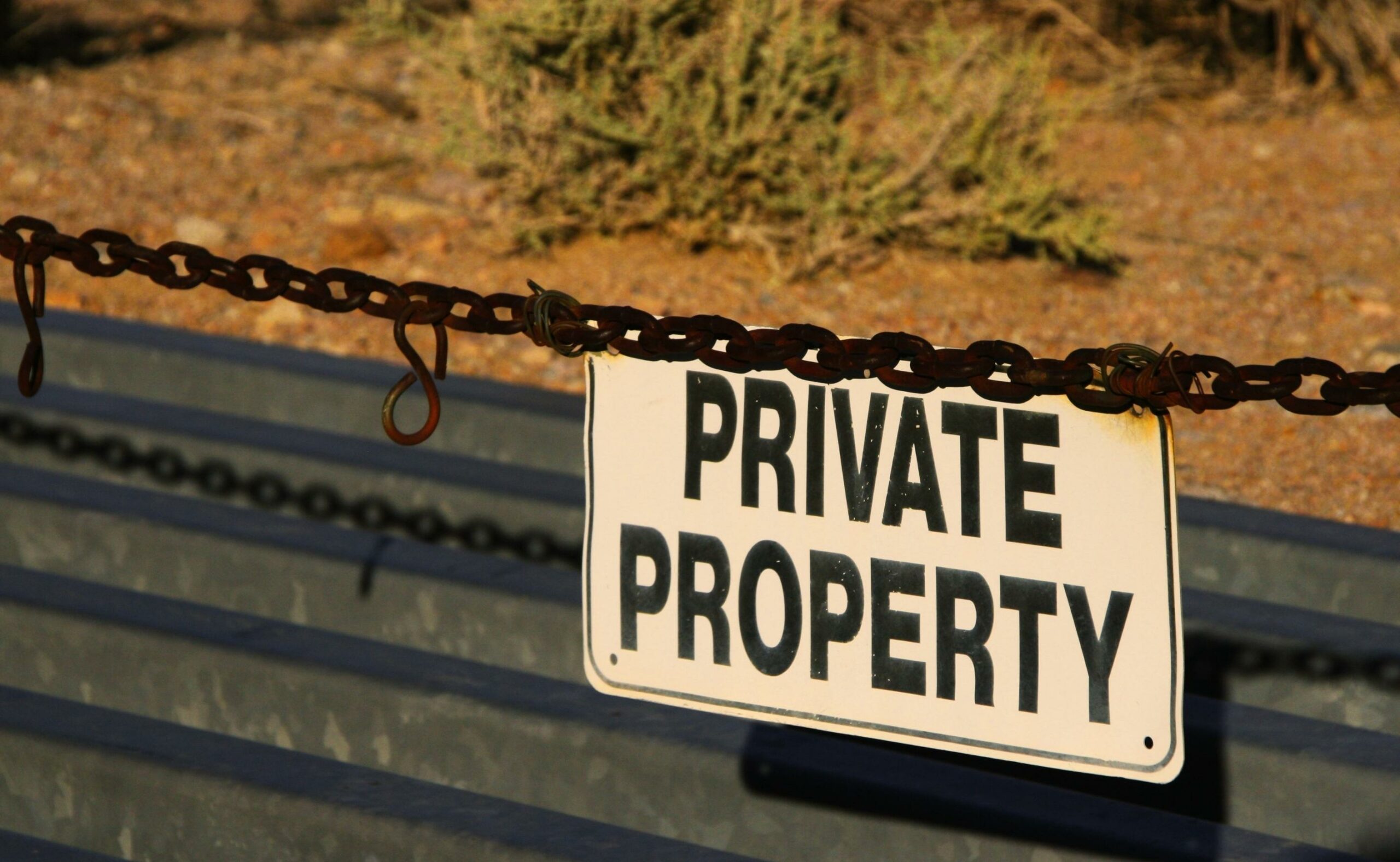 Private property sign hanging on a chain restricting access