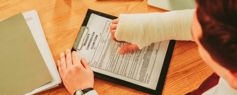 cropped view of worker holding broken arm compensation claim form