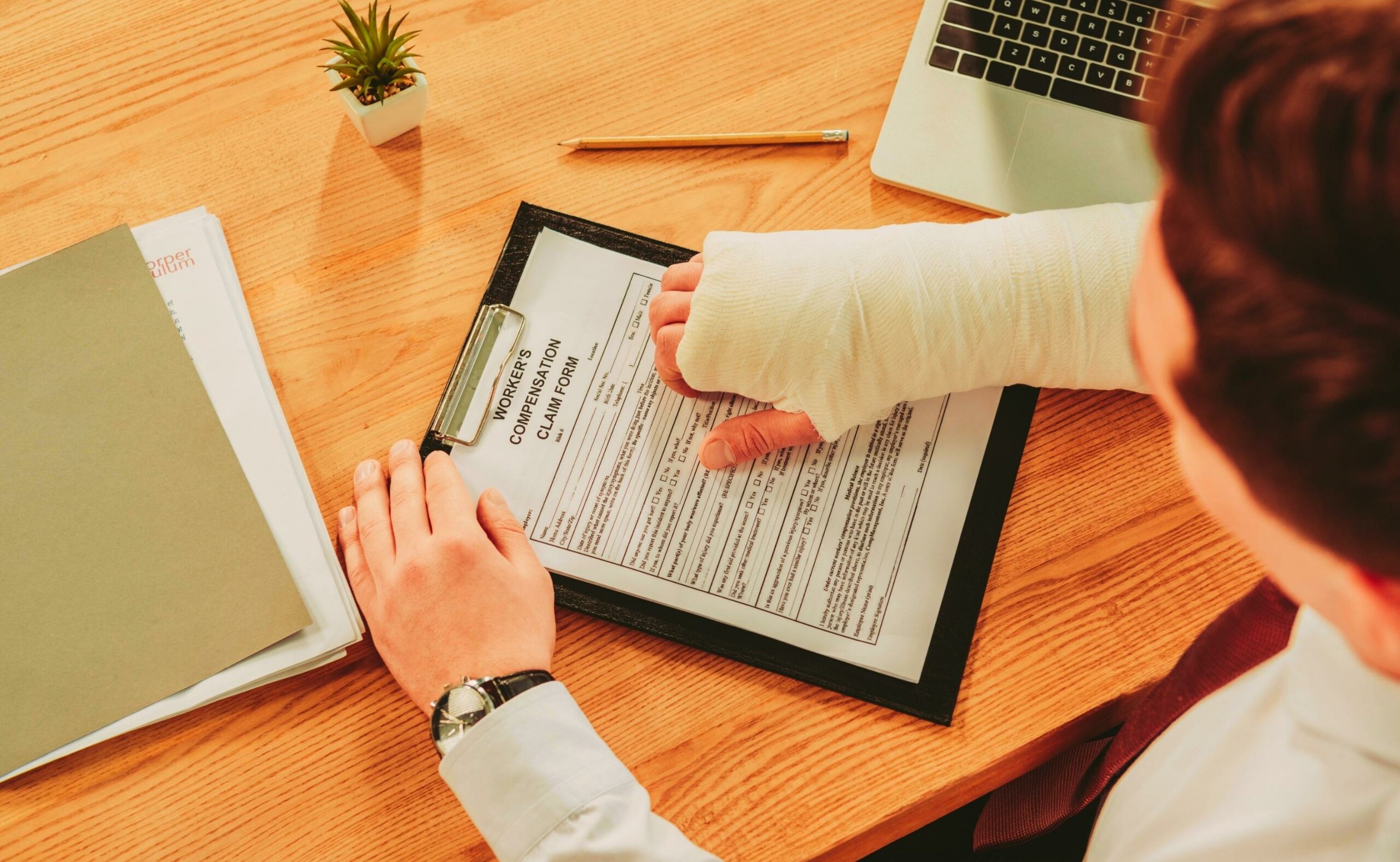 cropped view of worker holding broken arm compensation claim form
